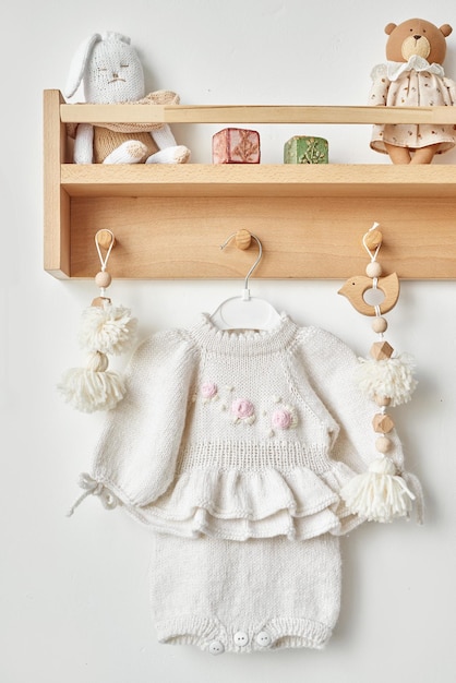 Knitted dress with embroidery on hanger on shelf kids clothes and accessories Needlework and knitting Hobbies and creativity Knit for children Handmade