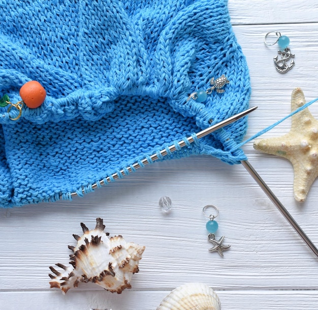 A knitted fabric from blue cotton yarn on a white background in a marine theme with sea shells