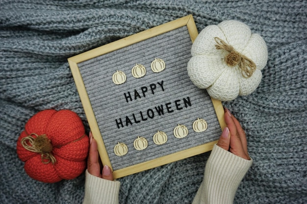 On a knitted gray background, a sign with the inscription - happy Halloween