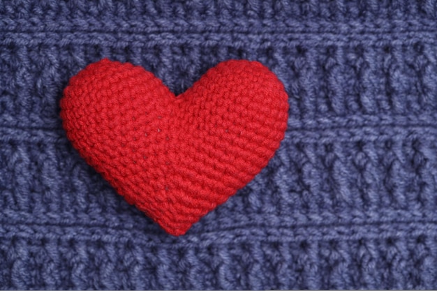 Knitted heart lies on a blue knitted napkin. Love concept. High quality photo