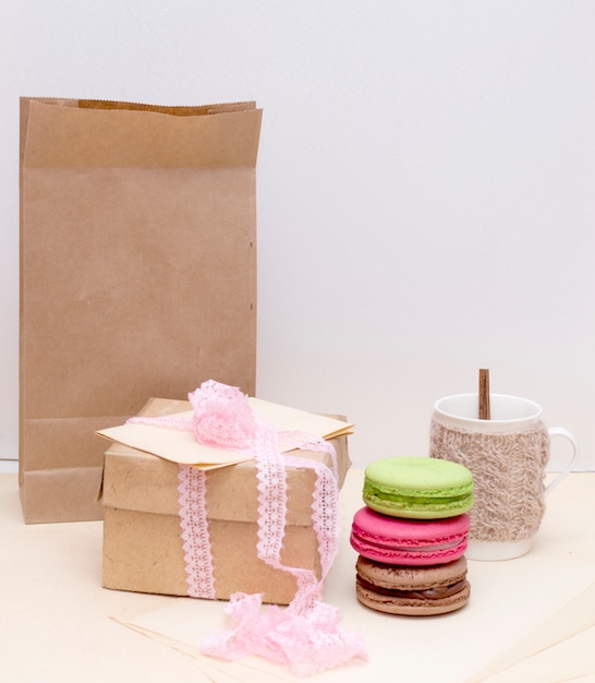 Knitted mug and colorful macaroons on rough paper bag  