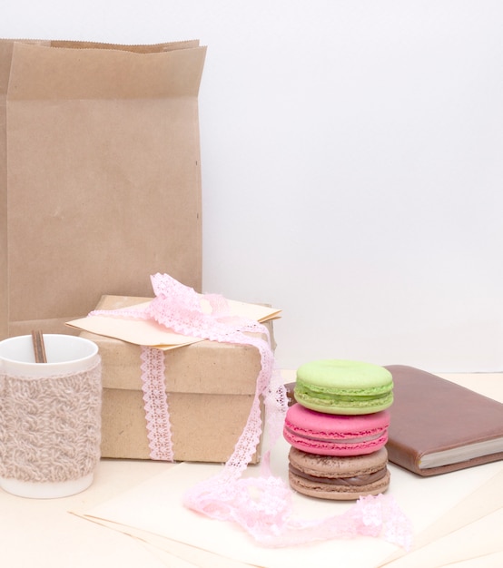 Knitted mug and colorful macaroons on rough paper bag  