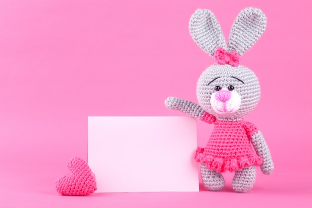 Knitted rabbit in pink dress. St. Valentine's Day decor. Knitted toy, amigurumi. Valentines day greeting card.