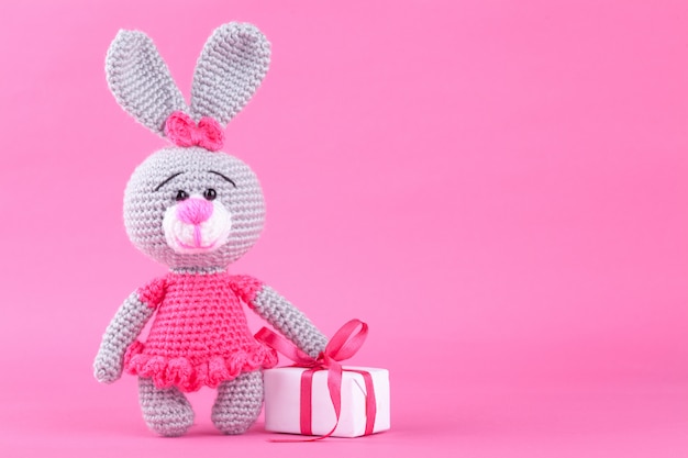 Knitted rabbit in pink dress. St. Valentine's Day decor. Knitted toy, amigurumi. Valentines day greeting card.