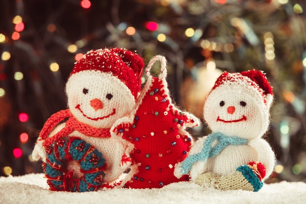 Knitted snowmen and handmade Christmas tree - home decorations on the snow