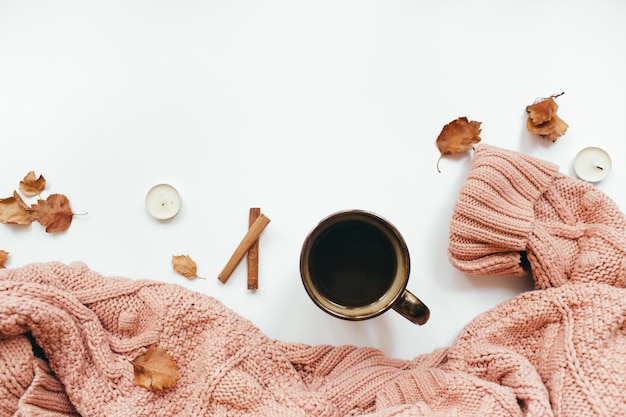 Knitted sweater cup of coffee autumn leaves cinnamon sticks candles on white background autumn