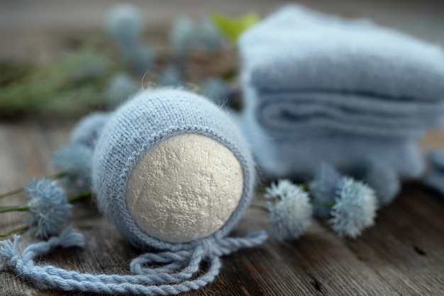 Knitted white clothes composition for newborn on the wooden table