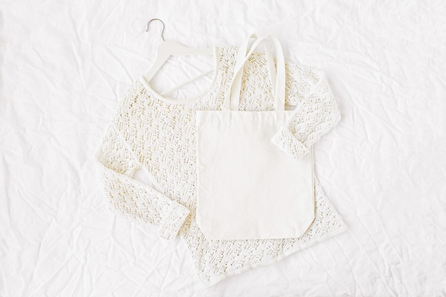 Knitted white sweater with  tote bag. Autumn/winter fashion clothes collage on white background. Top view flat lay.