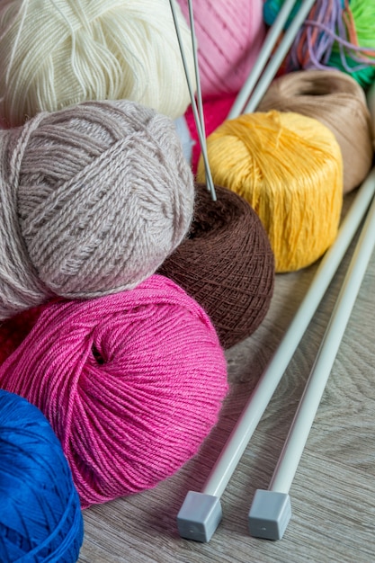 Knitting, Group of multicolor yarn and needles on grey wooden table. 