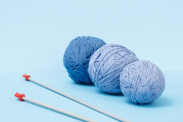 Knitting yarn balls and metal knitting needles on a blue background. Knitting concept.