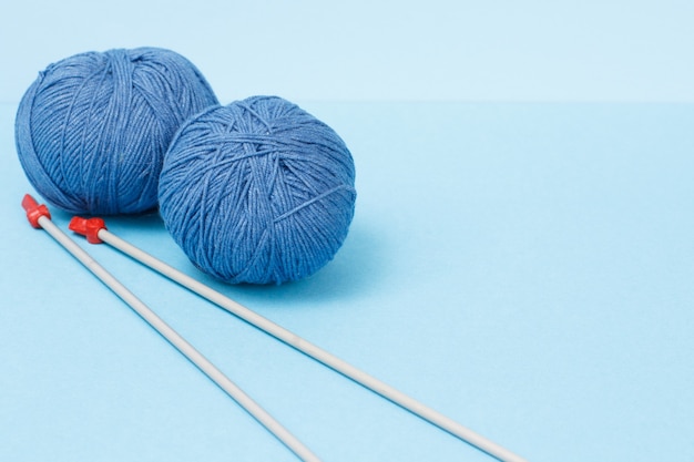 Knitting yarn balls and metal knitting needles on a blue background. Knitting concept.