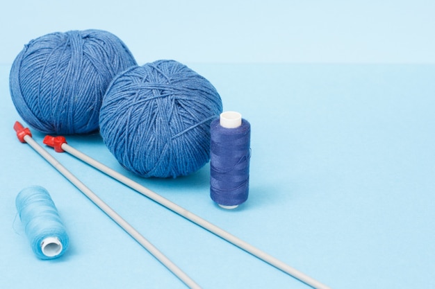 Knitting yarn balls, metal knitting needles and threads on a blue background. Knitting concept.