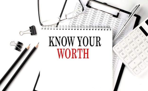 KNOW YOUR WORTH word on notepad with clipboard chart and calculator business concept