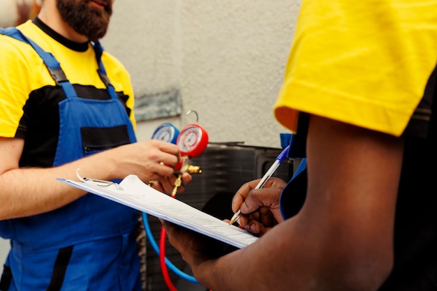 Knowledgeable professionals tasked to do air conditioner check, refilling refrigerant. Competent mechanics using manifold meters to exactly calibrate the pressure in HVAC system