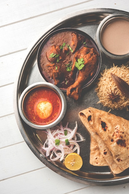 Kolhapuri chicken Thali is a popular Indian, asian food platter consists of poultry meat, egg curry with chapati ,rice, salad and sweet Gulab Jamun