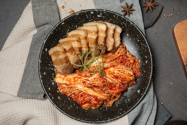 Korean Boiled Pork with preparing cabbage kimchi in black dish. Korean traditional cuisine. Fermented food.