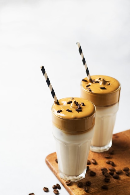 Korean dalgona coffee with brown foam in tall glass close up on white background