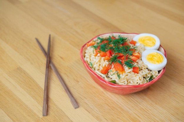 korean egg noodles in a plate with egg dill vegetables and chopsticks stands on the table