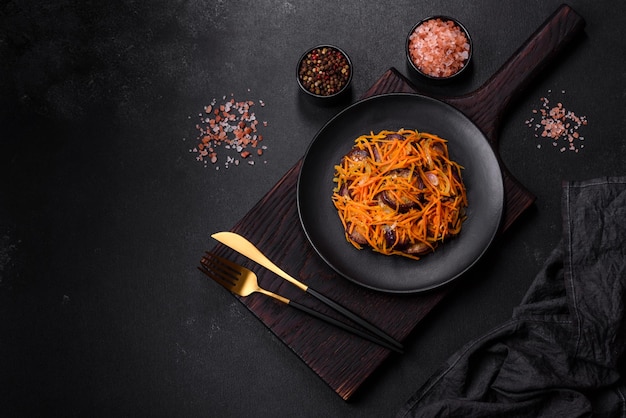 Korean salad with eggplant carrots garlic spices and herbs on a dark concrete background