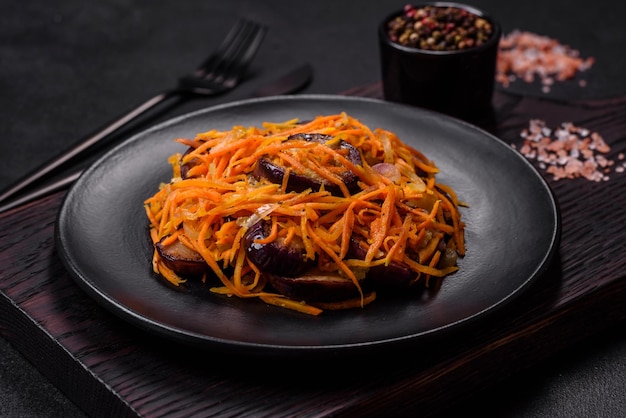 Korean salad with eggplant carrots garlic spices and herbs on a dark concrete background