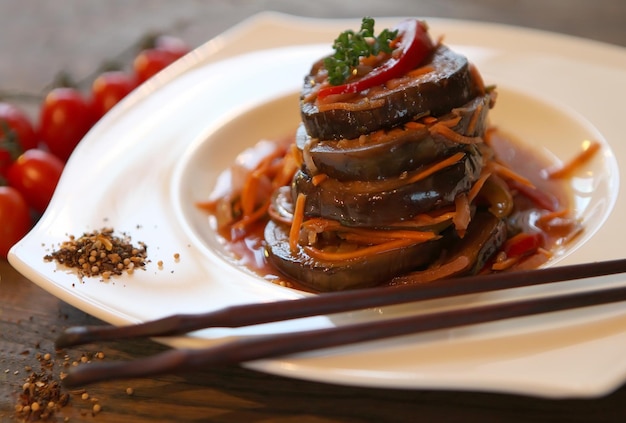 Koreanstyle carroteggplant salad with tomatoes on a dark wooden table