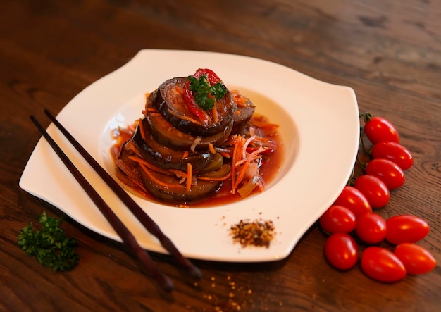 Koreanstyle carroteggplant salad with tomatoes on a dark wooden table