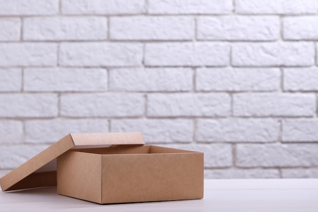 Kraft cardboard box on table against brick wall background