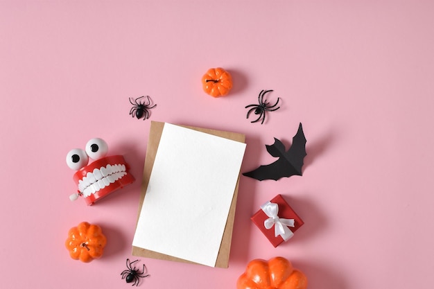 Kraft envelope next to various decorations for the Halloween holiday on a pink background Copy space Flat lay top view