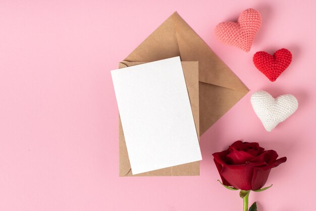 Photo kraft envelope with a blank sheet layout with a red rose and three hearts on a pink background banner for valentine's day postcard for february 14love minimalism