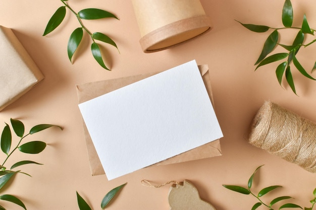 Kraft envelope with ecopackaging and leaves on a beige background