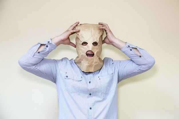 Photo kraft paper bag is on the man's head. holes for eyes. funny idea. guy is in panic.