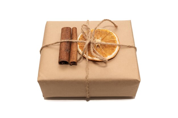 Kraft paper gift box with dried orange and cinnamon sticks. On white paper.