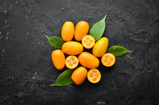 Kumquat on a black stone background Citrus fruits Top view Free space for your text