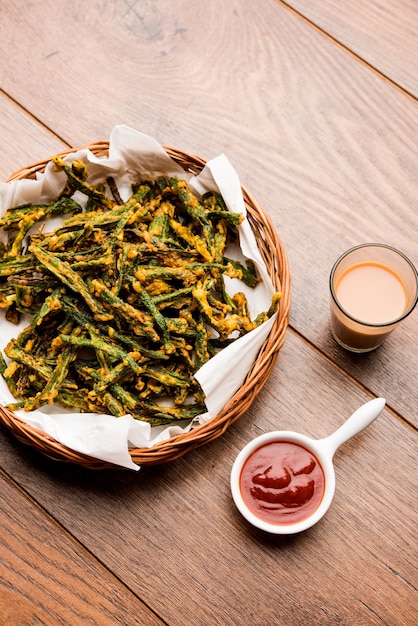 Kurkuri bhindi or crispy ladyfinger or okra fry recipe, served in a bowl with ketchup and hot tea. selective focus