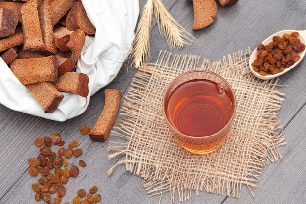 Kvas in glass with rye bread and raisins on wooden background