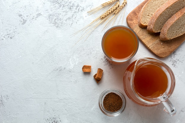 Kvass in a glass and a jug on a light space