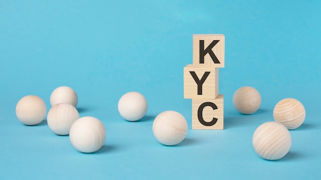 KYC text on wooden block with bright blue background