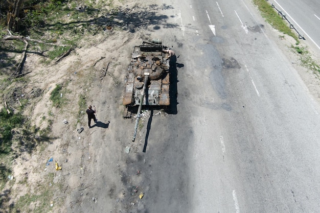 Kyiv region Ukraine May 15 2022 War in Ukraine Highway Kyiv Zhytomyr People take selfies against destroyed russian tank after russian atack in Febrary