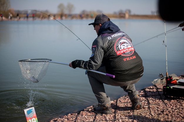 Kyiv, Ukraine April 16, 2018. A caucasian fisherman catches fish with a landing net on the lake.