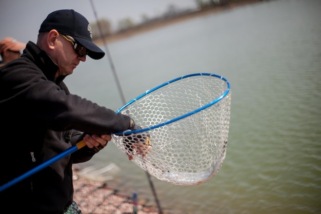 Kyiv, Ukraine April 16, 2018. A fisherman cuts off a fishing line for a fish in a landing net.