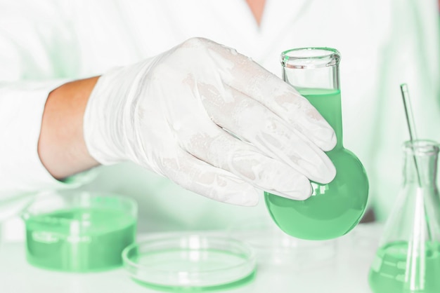 Lab scenario Lab assistant engages in manipulations within the laboratory Donning lab coat Notable green shades Glass instruments used Dedicated to plant research in the green laboratory