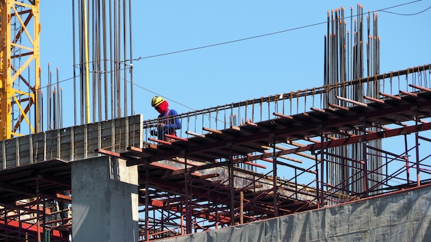 Labor working on construction site and building tower with concrete and metal material.