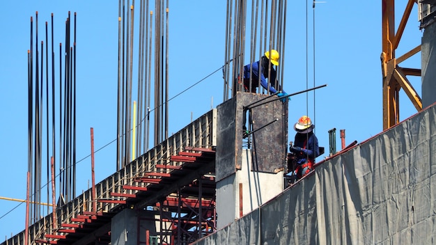 Labor working on construction site and building tower with concrete and metal material.