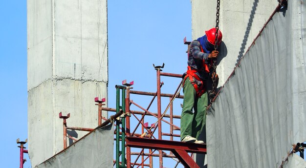 Labor working on construction site and setting vinyl and steel to cover the building and blue sky.