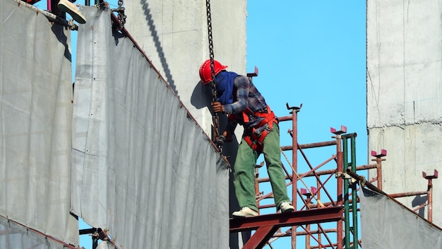 Labor working on construction site and setting vinyl and steel to cover the building and blue sky.