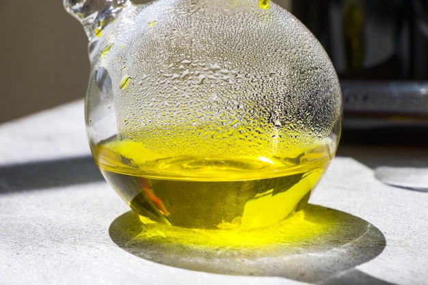 Laboratory glass with yellow color reagent with shadows and reflection on a wooden surface