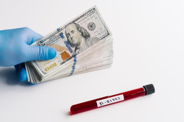 Laboratory sample of blood testing for coronavirus diagnosis stack of money near against white background Covid19 economic impact Economic crisis