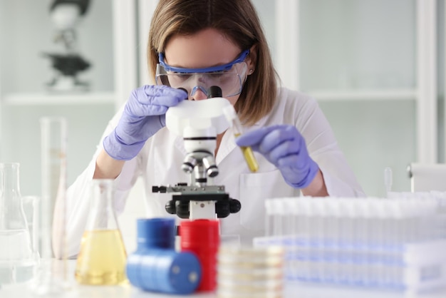 Laboratory worker examines samples of substances under microscope detection of diseases of