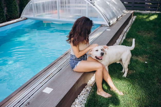 Labrador and girl enjoy the blue water of a swimming pool in summertime