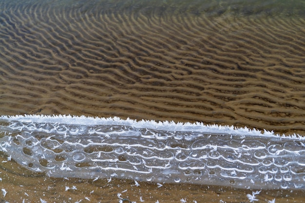 Lace patterns of the frozen water edge on the pond